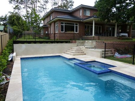 Light blue pool with spa tiled seat and retaining walls