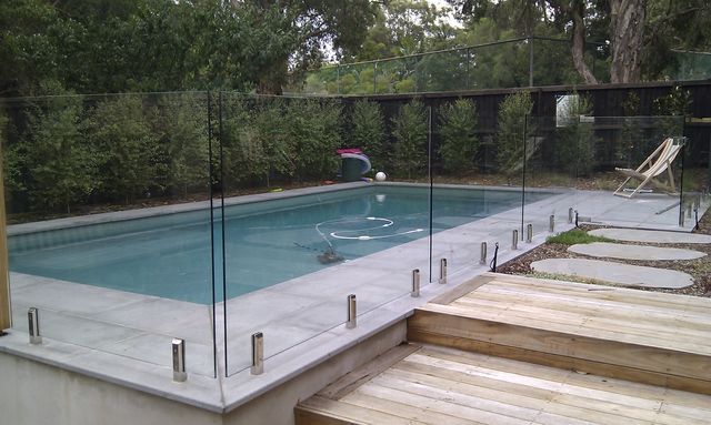Fully tiled mist green pool with glass fencing and decking