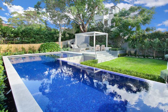 Royal blue fully tiled pool with infinity edge and cabana