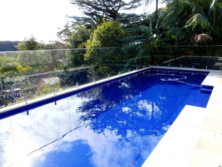 Fully tiled royal blue pool with glass fencing