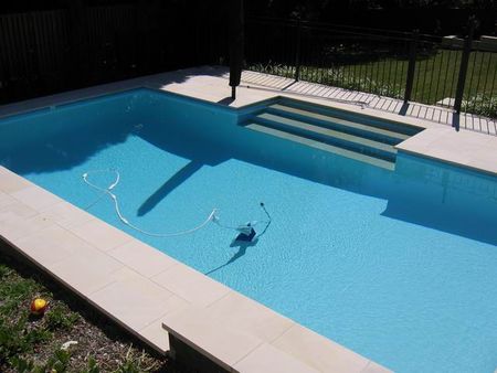 Light blue pool with wide steps and cleaner