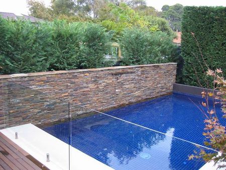 Fully tiled royal blue pool with stack stone feature wall