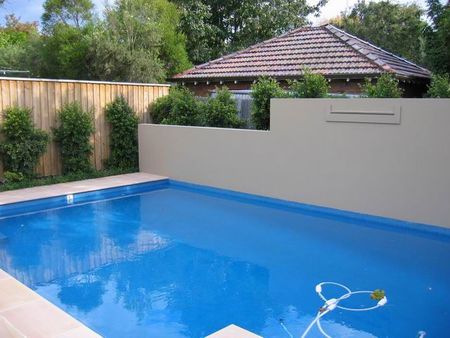 bright blue pool with stepped rendered wall and fountain