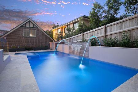 Twilight photo of Fully tiled sky blue pool with water features