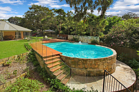 Out of ground pool with rounded stone clad wall and decking